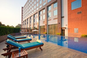 Un hôtel doté d’une piscine sur le toit, de chaises longues et d’une façade moderne.