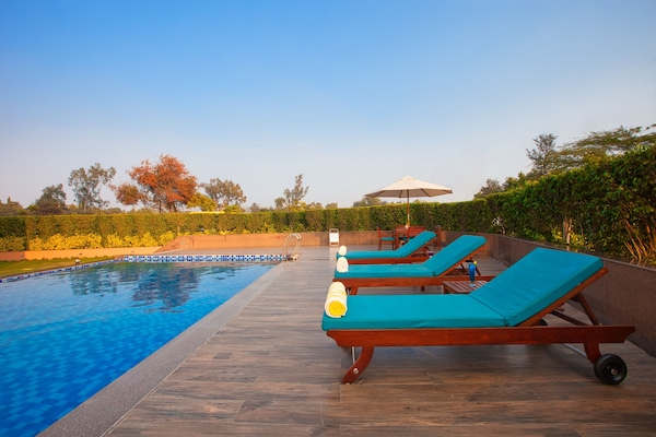 Una piscina al aire libre, sillones reclinables de piscina