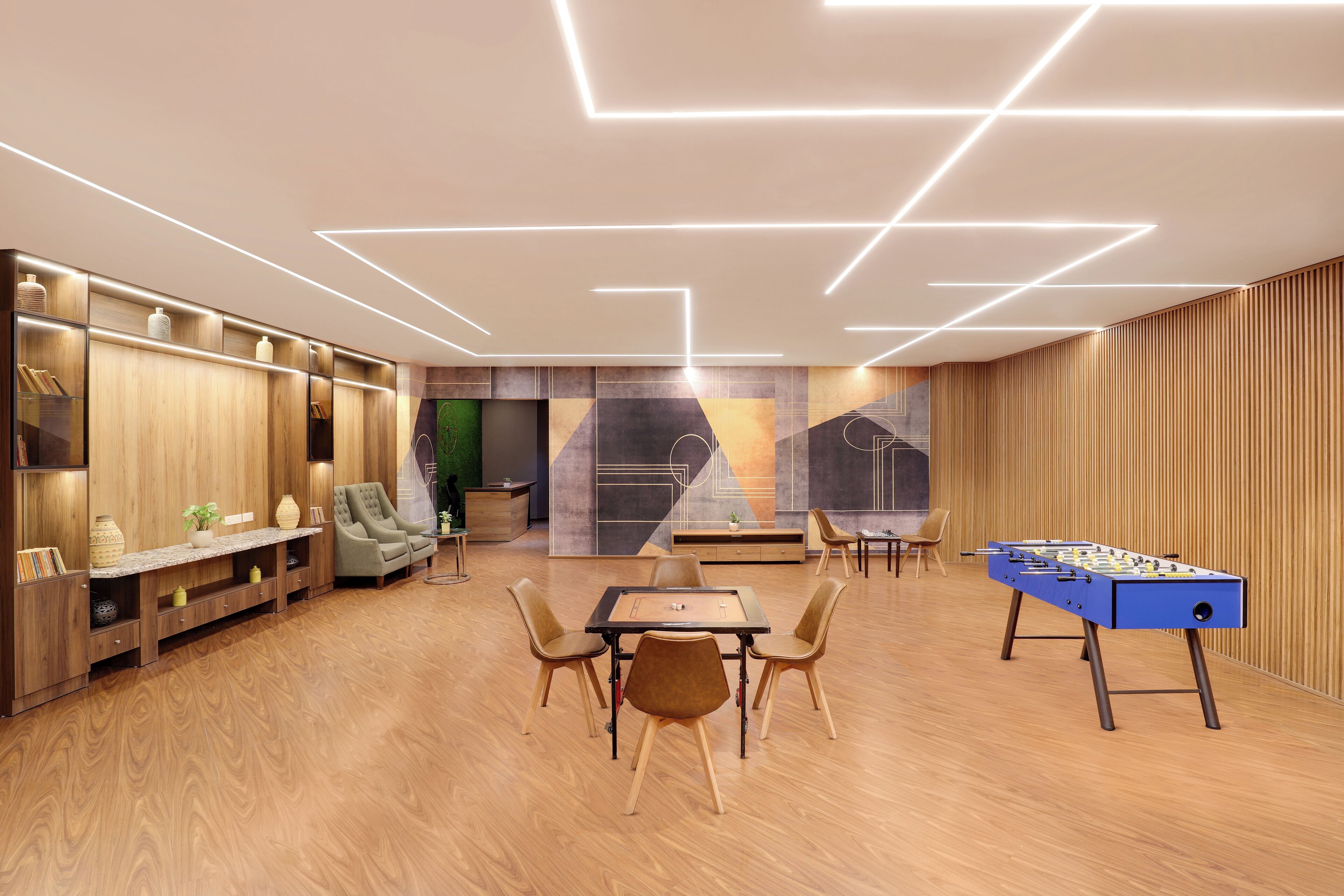 A modern lounge area with a foosball table, seating, and a large abstract mural on the wall.