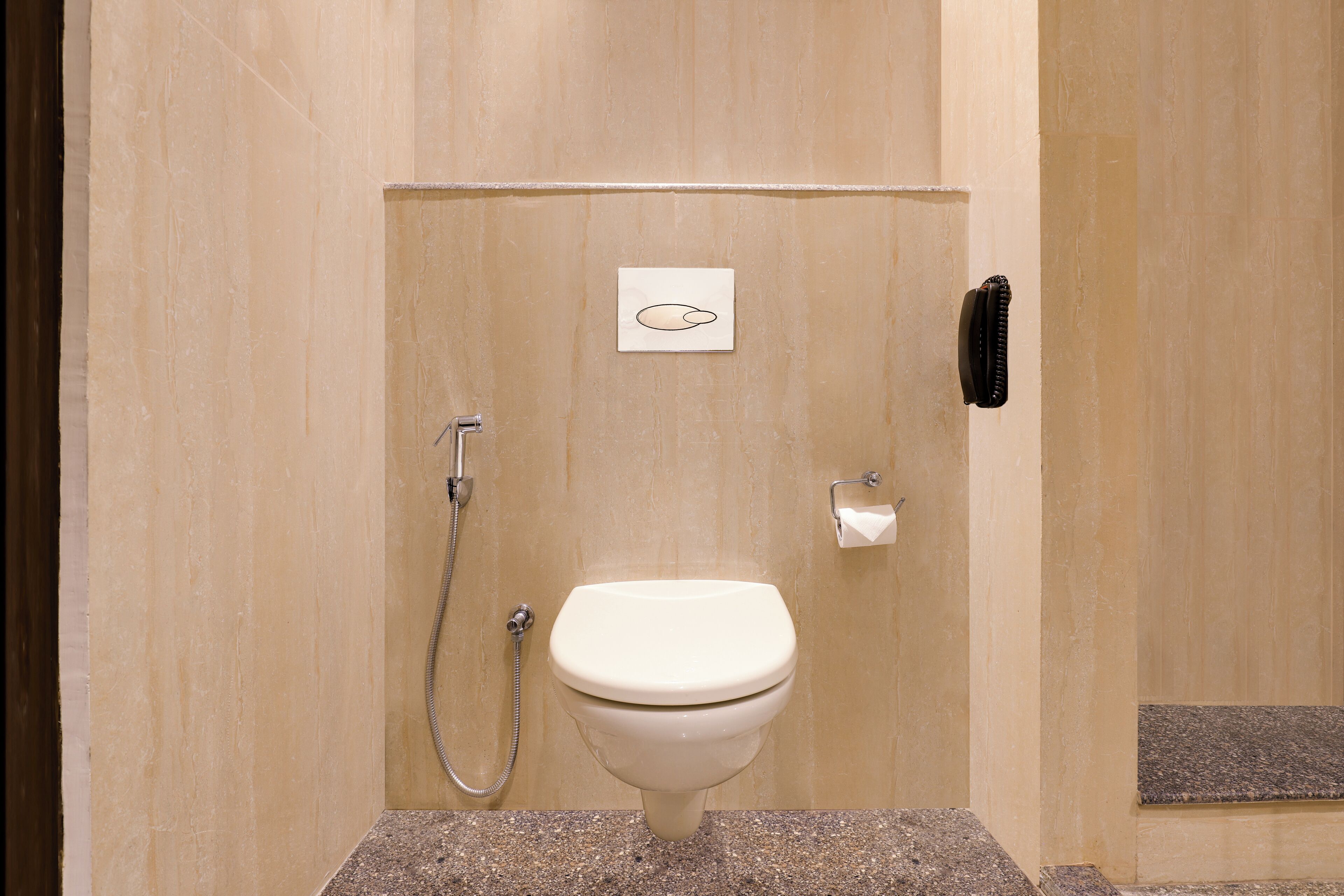 Een compacte, privé badkamer met toilet, douche en een handdoekhouder.
