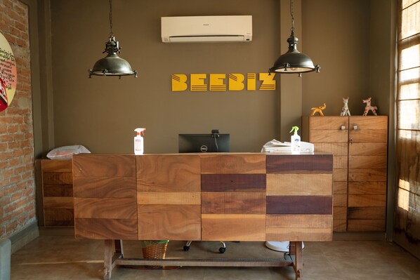 A reception desk with a wooden design, an air conditioner, and two hanging lamps. - Hotel Beebiz Guindy (Chennai)