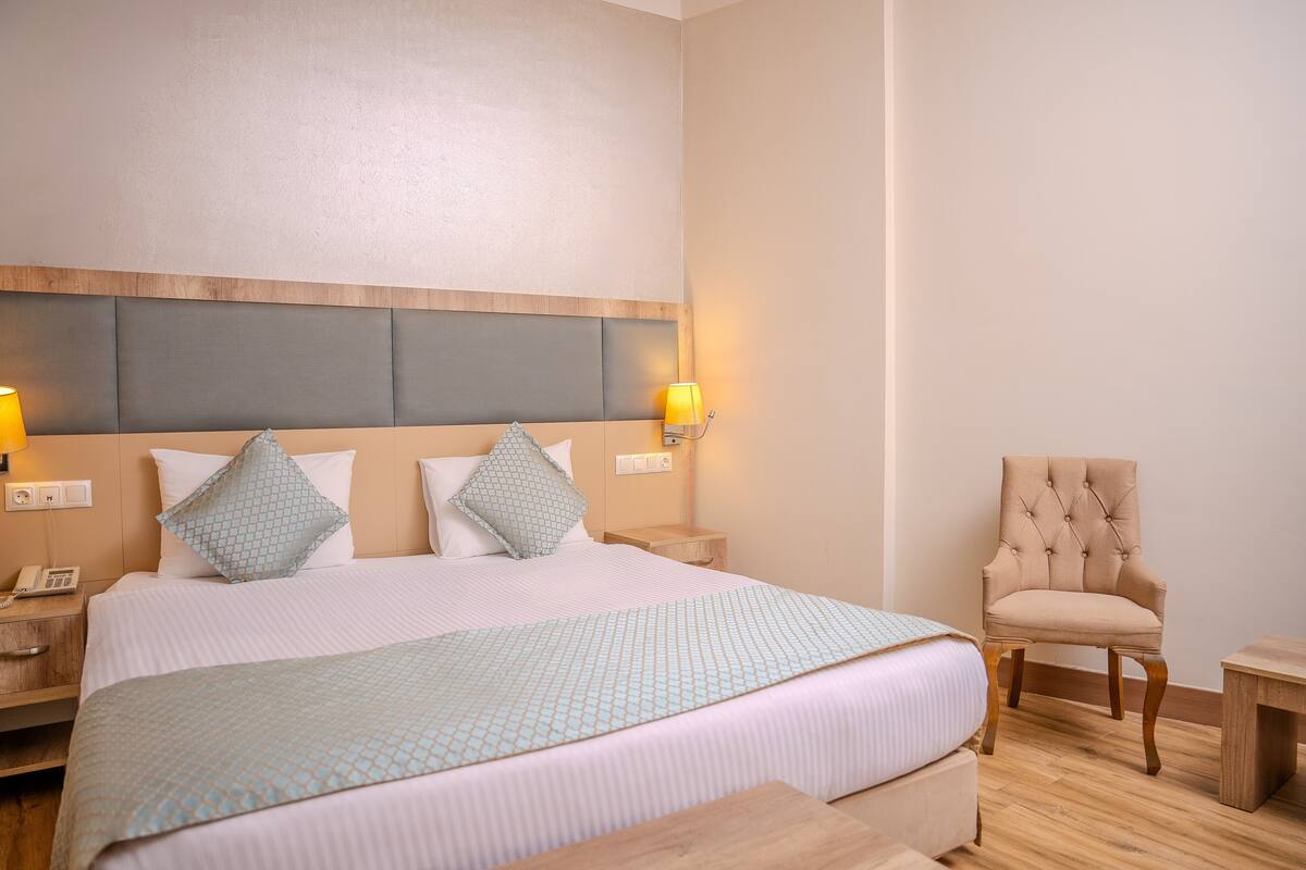A hotel room with a large bed, two bedside tables, a chair, and a nightstand.