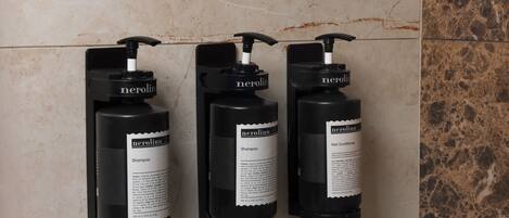 Three black shampoo bottles with pump dispensers labeled 'nerolinn' on a tiled wall.