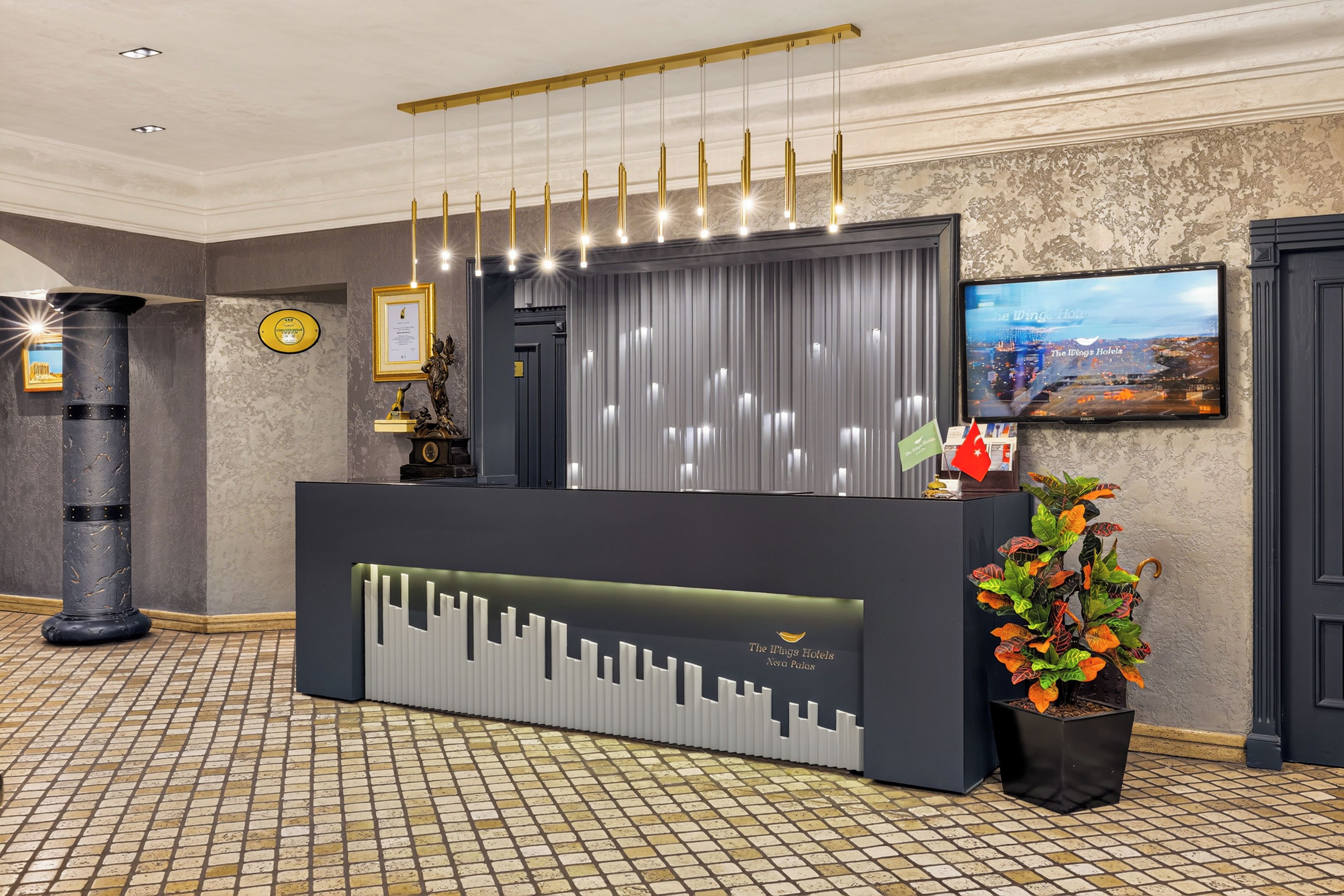 Uma receção com design moderno, um certificado emoldurado na parede e uma televisão a exibir uma vista urbana.