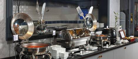 A buffet setup with various food containers, utensils, and a sign indicating 'Menemen & Menemen'.