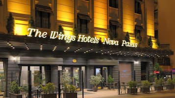 Wings Hotels Neva Palas med en moderne facade, udendørs siddeområde og oplyst skiltning.