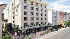 Un hotel con fachada clásica, varios balcones y un café en la planta baja con terraza.