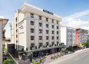 A hotel with a classic facade, multiple balconies, and a ground-level cafe with outdoor seating.