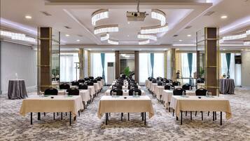 Un salón de conferencias con mesas y sillas dispuestas para una reunión.