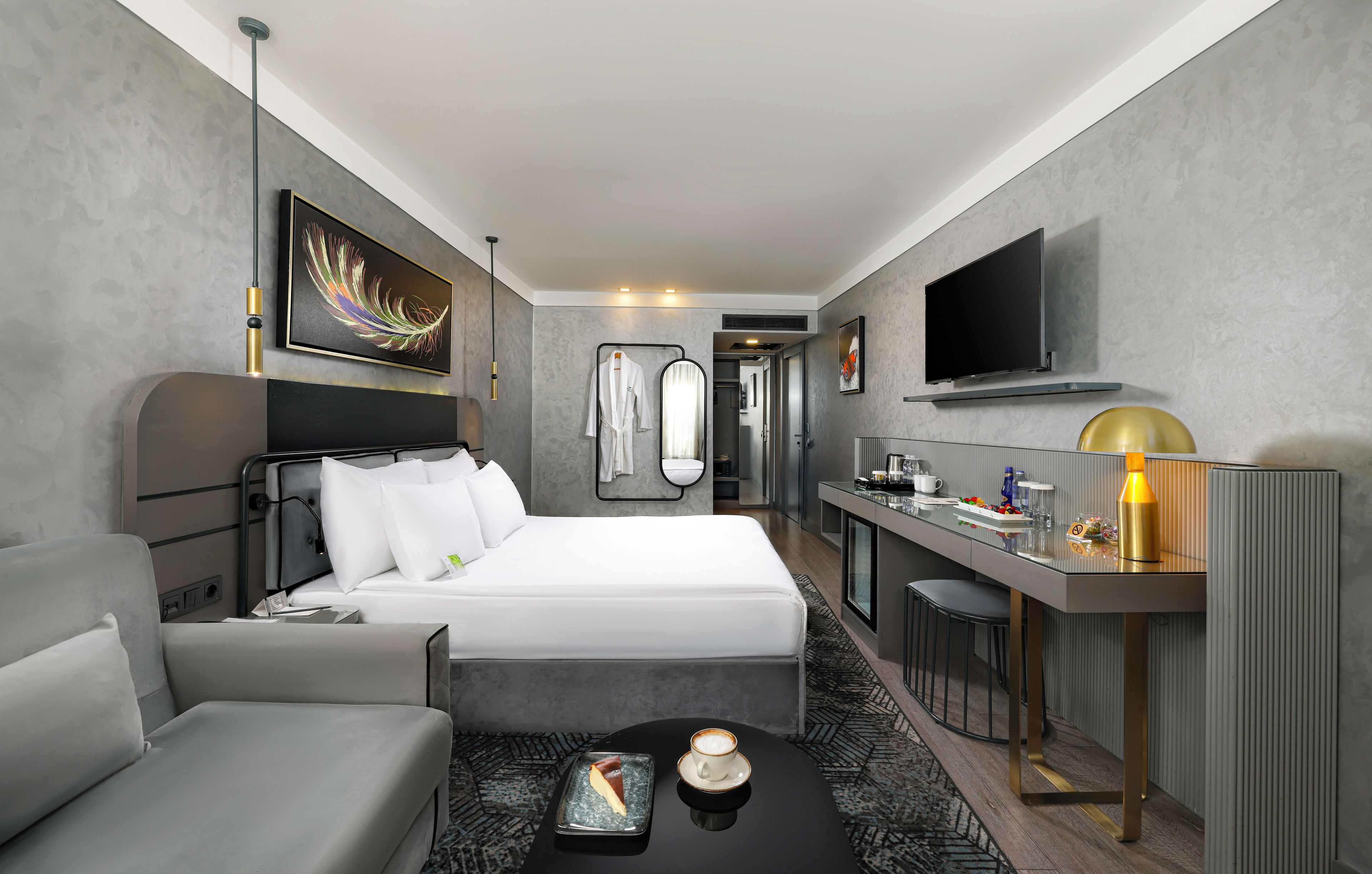 A modern hotel room with a bed, a desk, a chair, a TV, and a coffee table.
