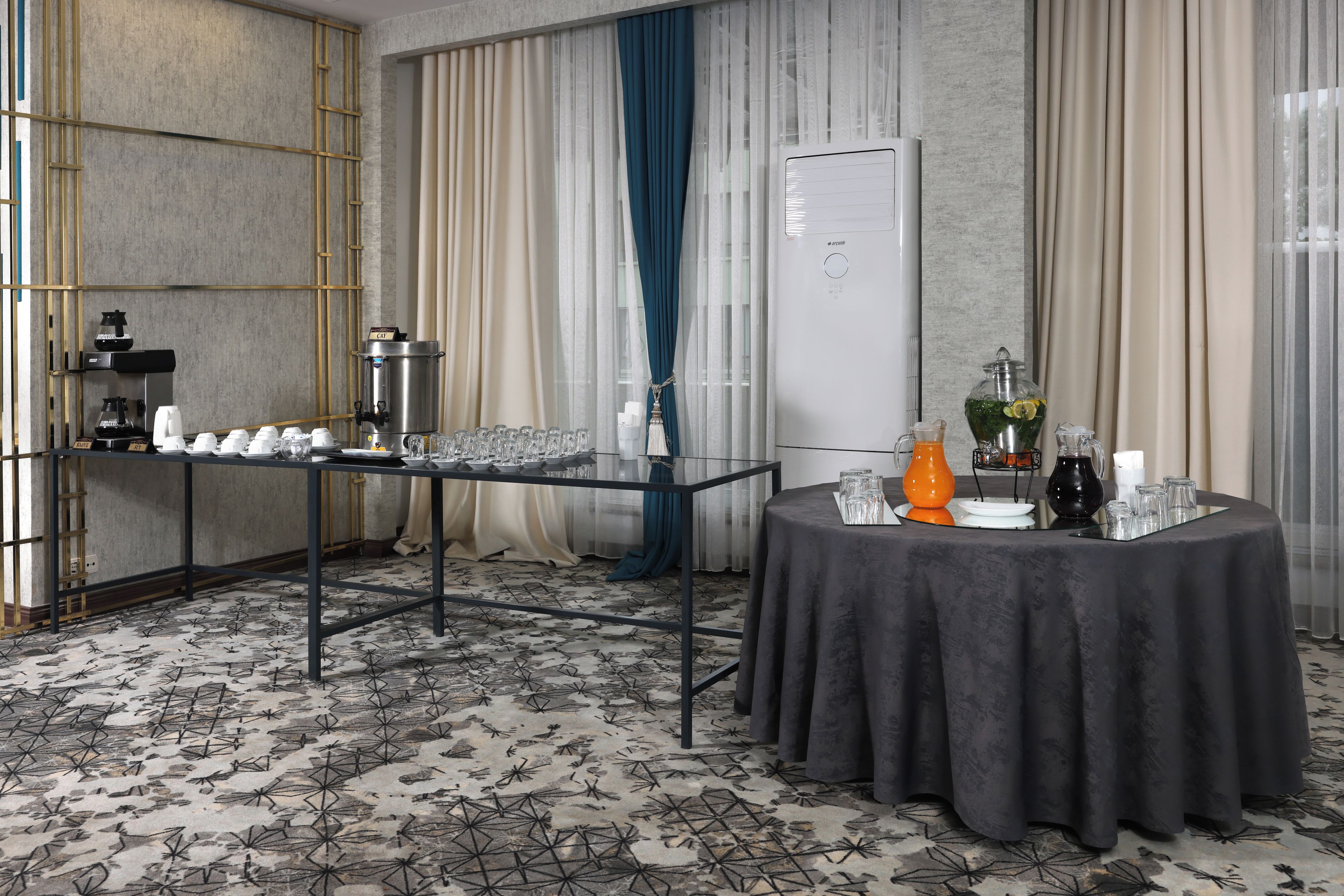 Um quarto com espaço para buffet, estação de café e mesa com dispensador de bebidas.