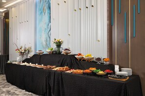 A buffet table with various food items and a vase of flowers. - The Wings Hotels Neva Palas (Ankara)