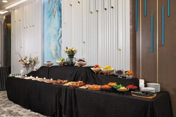 A buffet table with various food items and a vase of flowers.