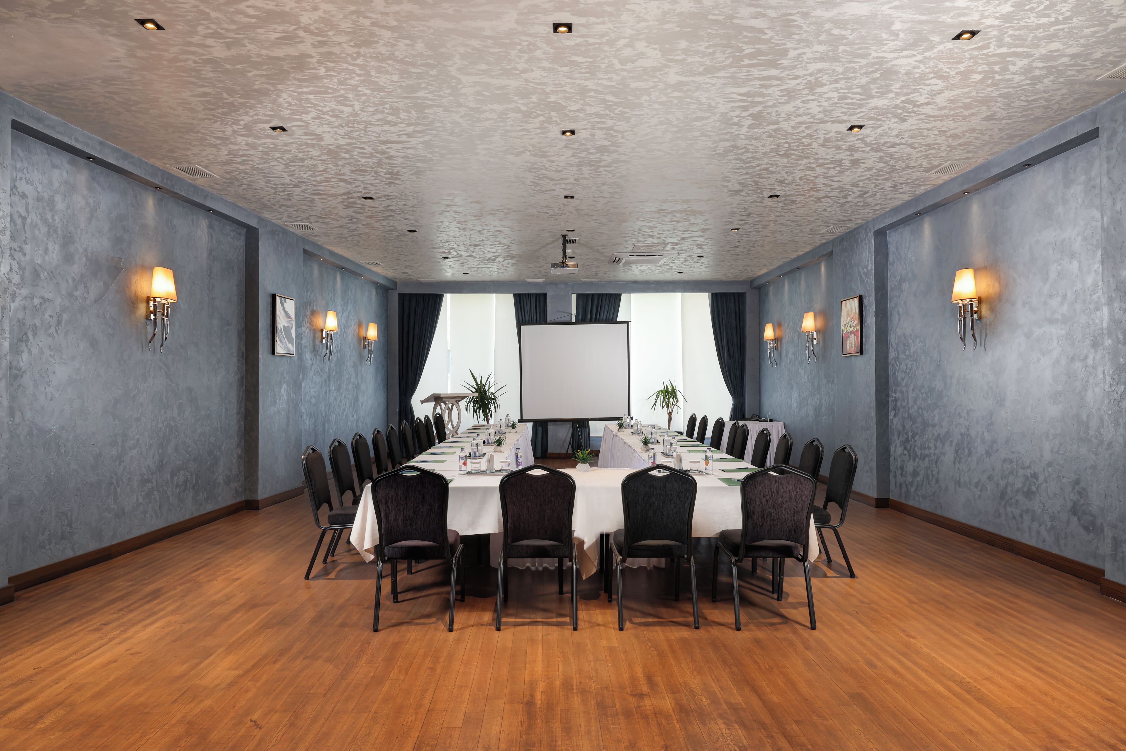 A conference room with a long table, chairs, and wall-mounted lamps.
