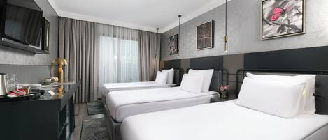 Habitación de hotel con dos camas, un escritorio, un televisor de pantalla plana, cafetera y obras de arte en las paredes.