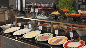 Un bufé con diversos alimentos, como queso, carnes, frutas y verduras.