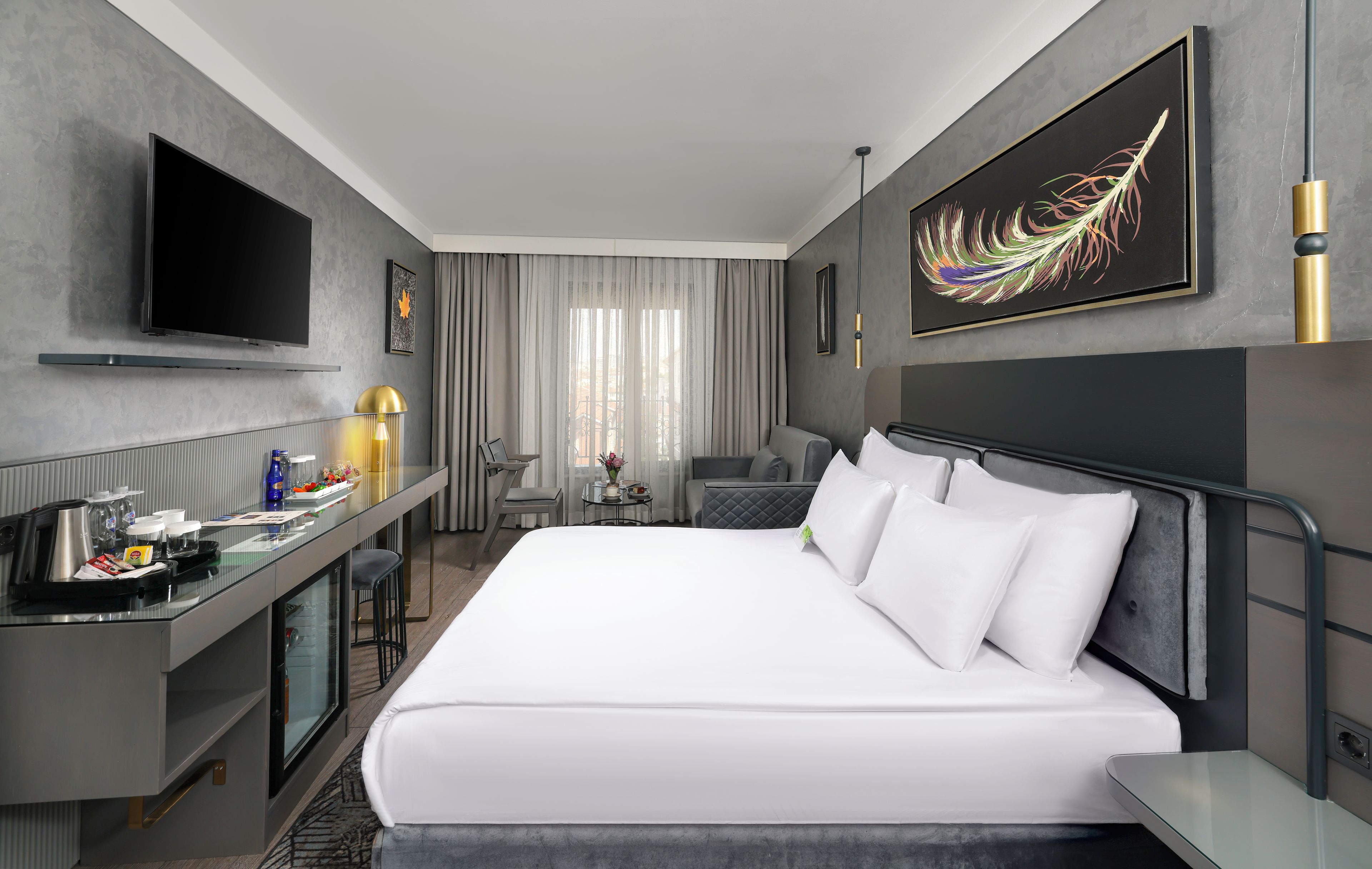 Habitación de hotel con una cama grande, un escritorio, un televisor de pantalla plana, un minibár y un área de comedor.