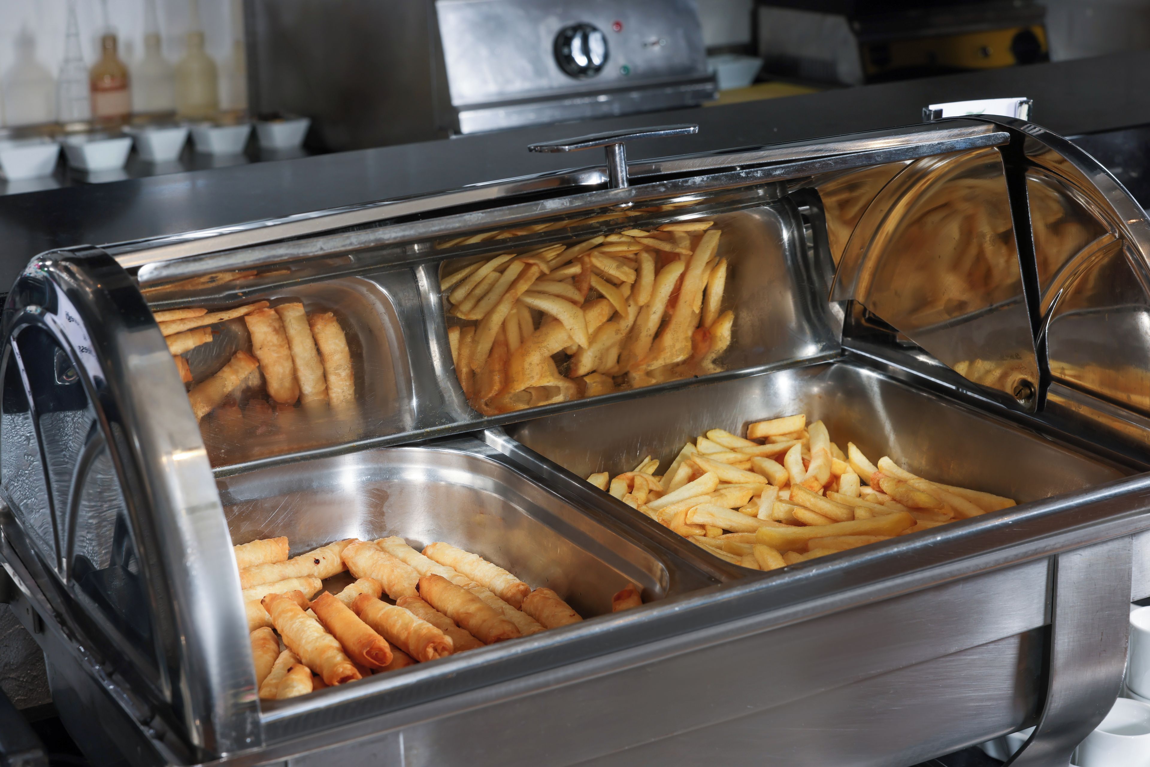 Un buffet proposant une variété de plats, notamment des frites et des rouleaux de printemps.