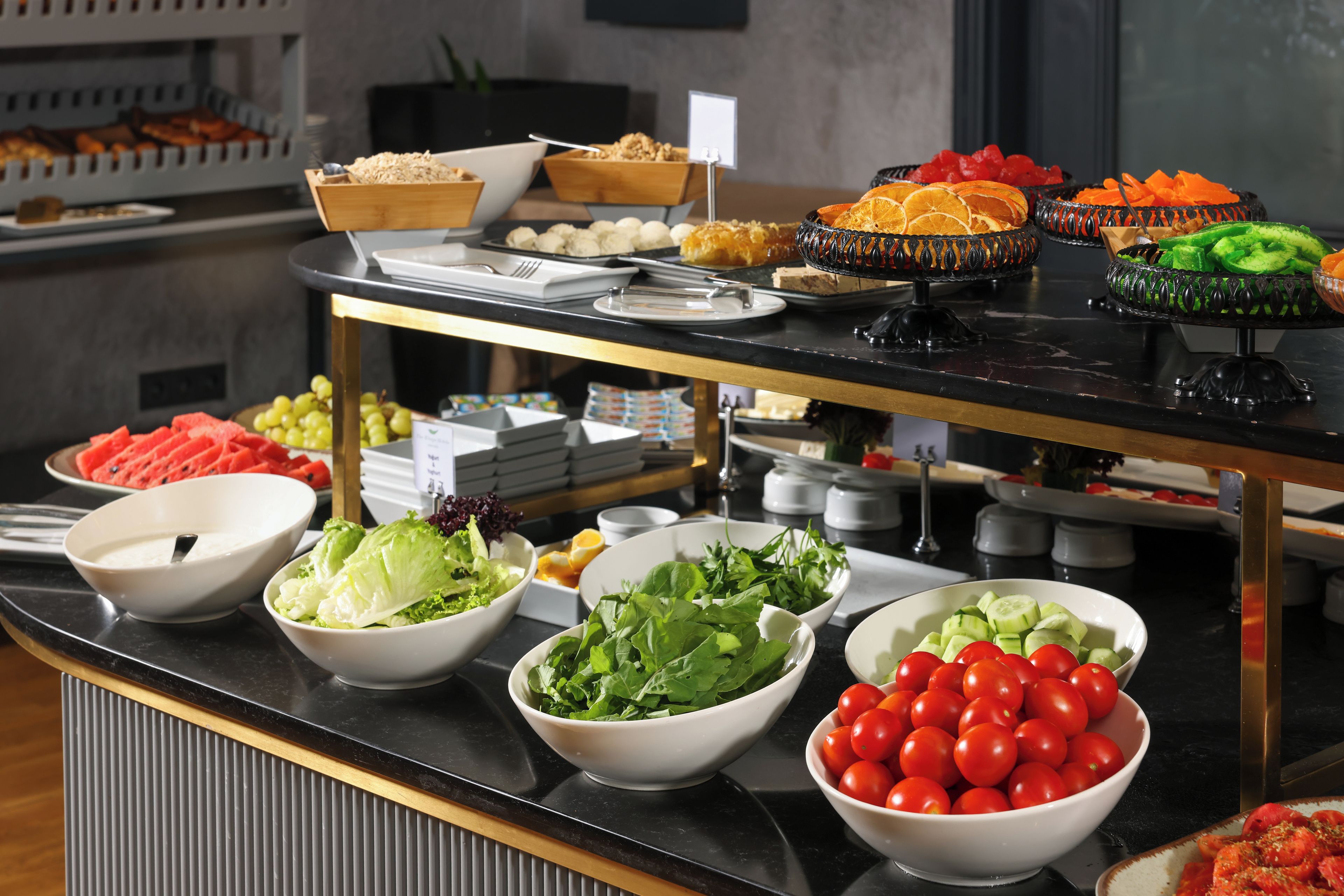 Ein Buffet mit verschiedenen Speisen, darunter Salate, Früchte und Gemüse.