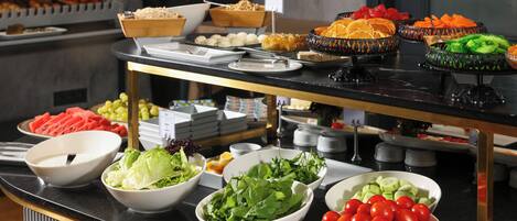 Un bufé con diversas opciones de comida, como ensaladas, frutas y verduras.