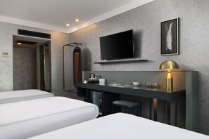 A modern hotel room with a flat-screen TV, a framed feather artwork, a minibar, and a massage chair.