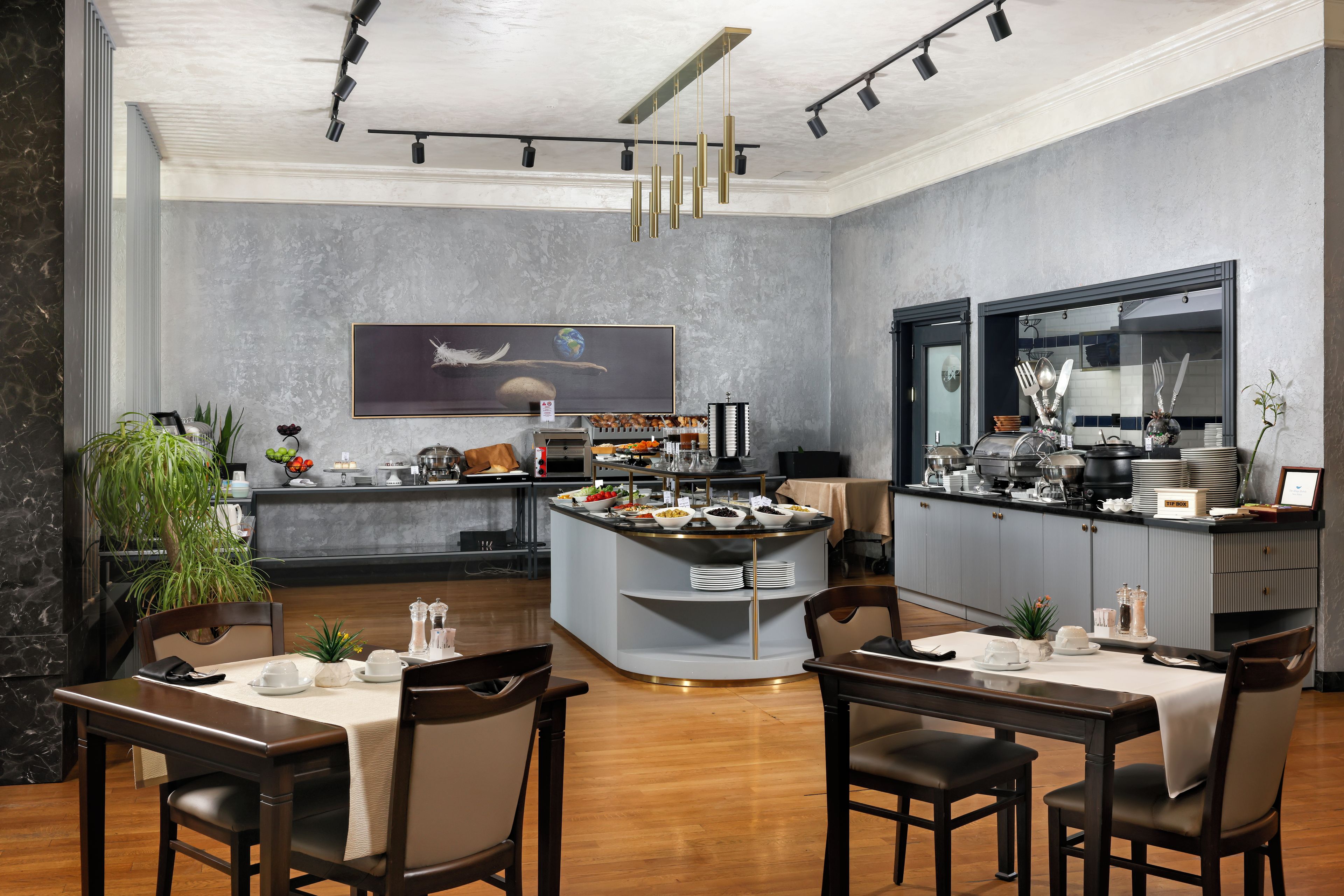 A modern kitchen with a central island, dining area with chairs, and a large painting on the wall.