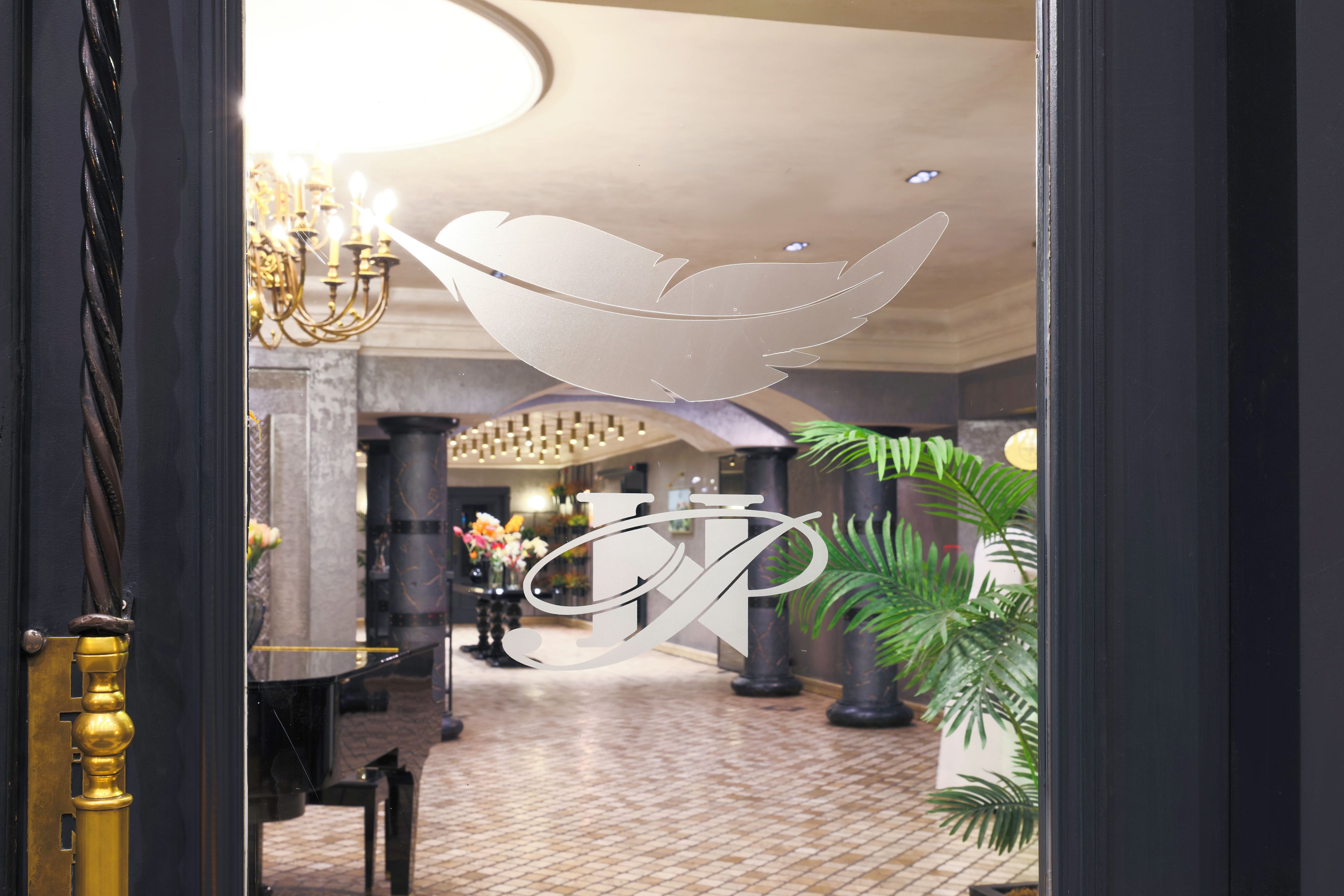 A lobby with a chandelier, a reception desk, and a large decorative letter 'P' on the wall.