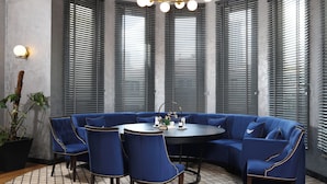 Un rincón con asientos, una mesa redonda, sillas tapizadas en azul y una planta en maceta.