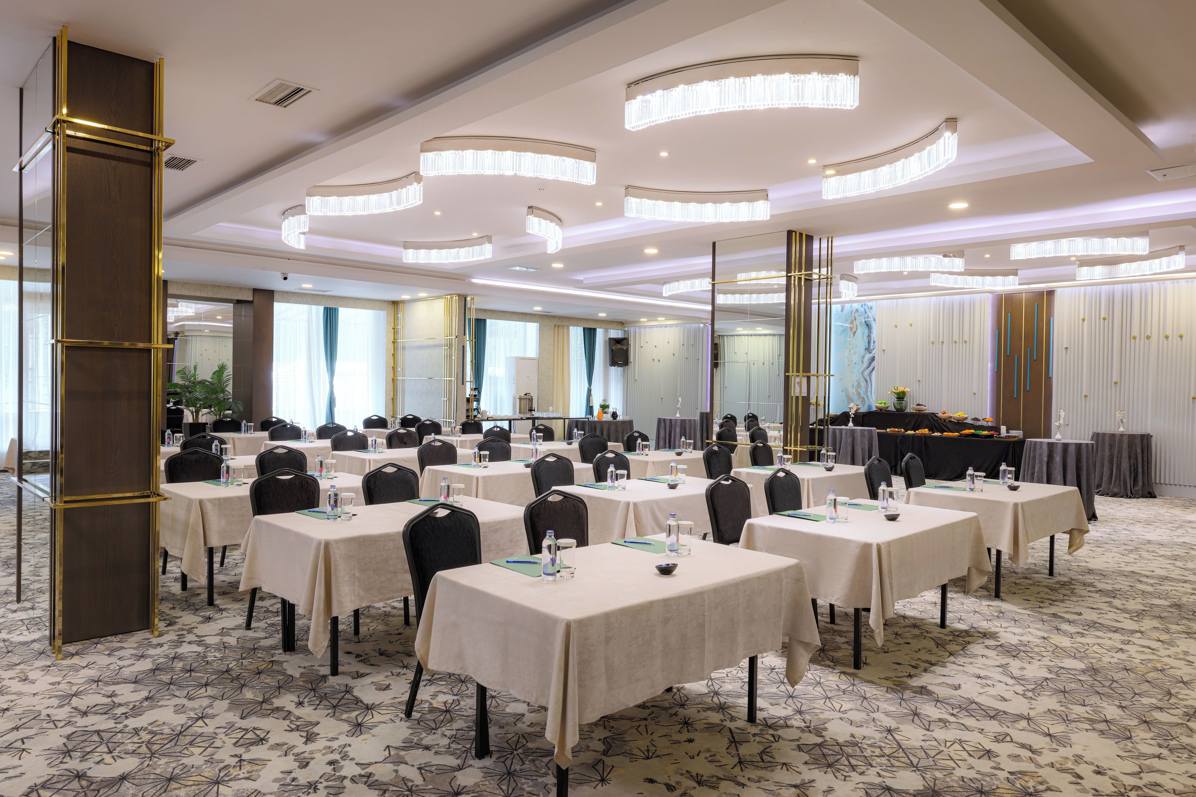 Un salón de conferencias con varias mesas, sillas y un escenario con un atril.