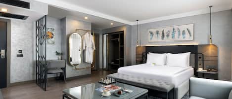 Habitación de hotel moderna con una cama grande, una mesita de centro de cristal, un sofá y un cuadro en la pared.