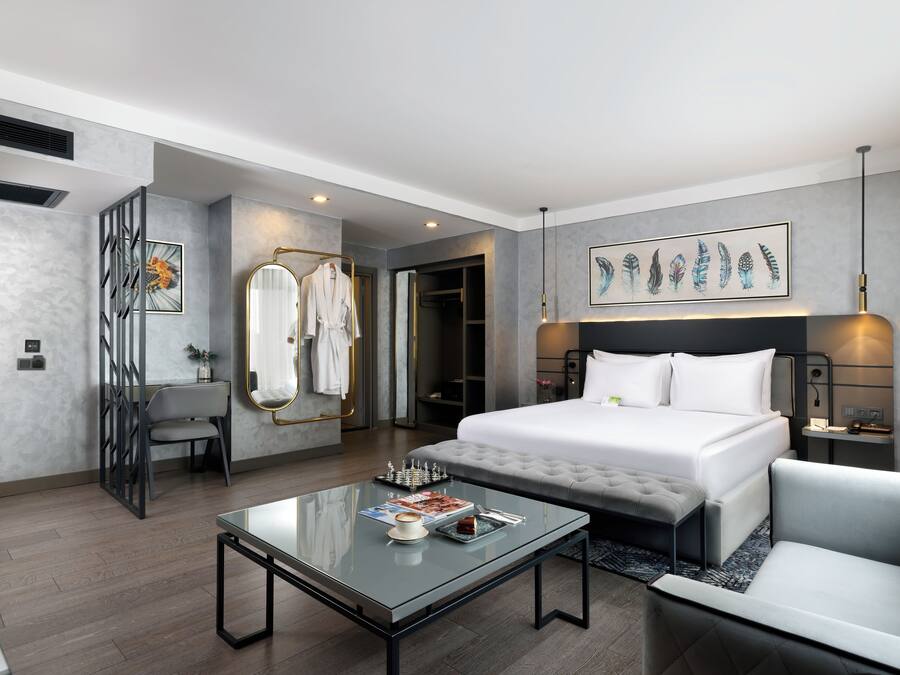 Une chambre d’hôtel moderne avec un grand lit, une table basse en verre, un canapé et un tableau au mur.