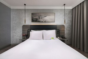 A modern hotel room with a large bed, a nightstand, a phone, and a painting on the wall. - The Wings Hotels Neva Palas (Ankara)