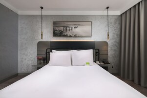 Una habitación de hotel moderna con una cama grande, una mesita de noche, un teléfono y un cuadro en la pared.