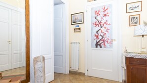 A hallway with white doors, a radiator, and a framed painting of a cherry blossom tree. - La Masseria (Capua)