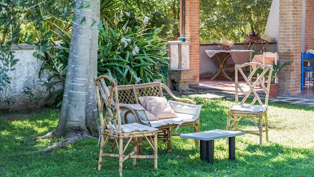 A covered outdoor seating area with wicker furniture and a brick wall. - La Masseria (Capua)