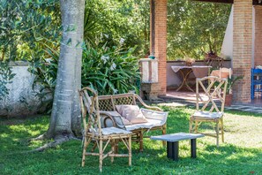 A covered outdoor seating area with wicker furniture and a brick wall. - La Masseria (Capua)