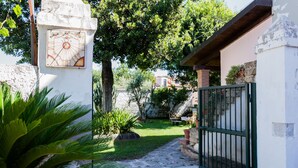 A courtyard with a gate, a sundial, and a small garden area. - La Masseria (Capua)