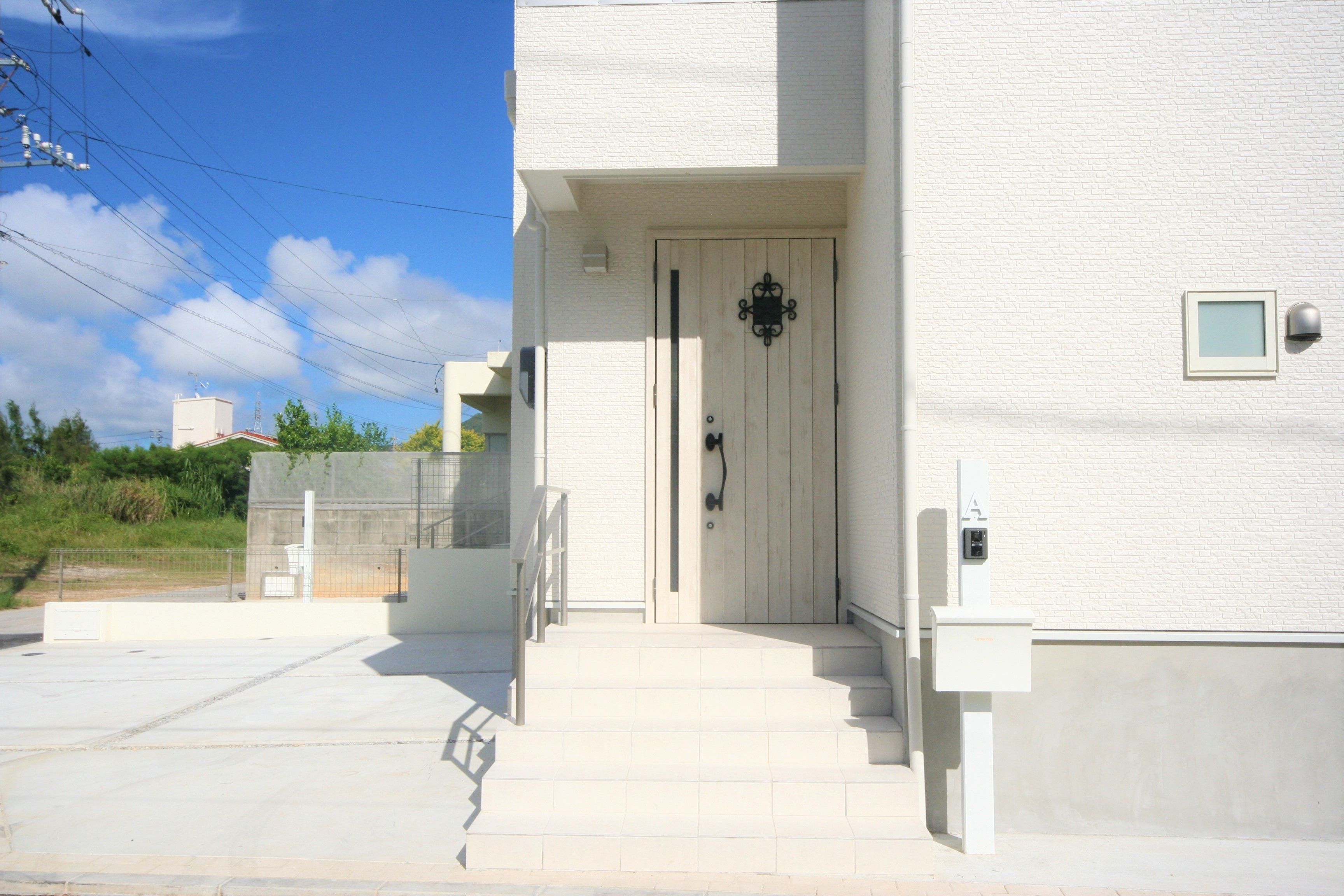 A white building with a wooden door, a small window, and a mailbox.