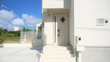 A white building with a wooden door, a small window, and a mailbox.