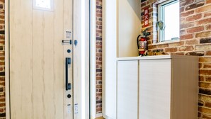 Una habitación con puerta de madera, pared de ladrillo y un armario blanco con un extintor encima.