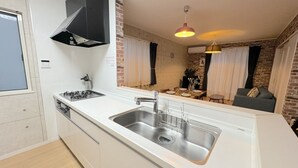 Una cocina compacta con un lavamanos de acero inoxidable, una estufa a gas y una campana extractora negra.