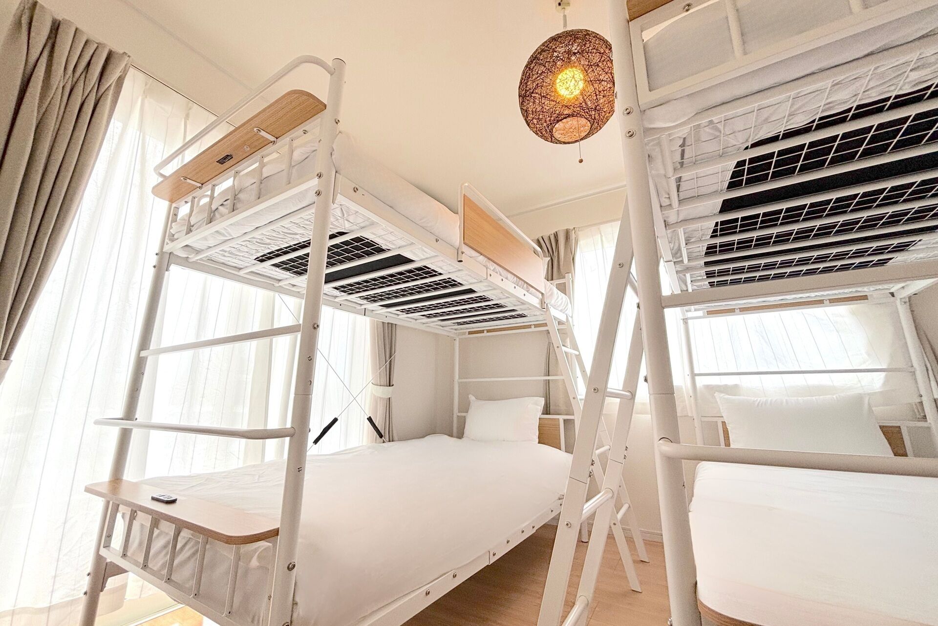 Ein Schlafraum im Mehrbettzimmer-Stil mit Etagenbetten, Deckenventilator und einem Fenster mit Vorhängen.