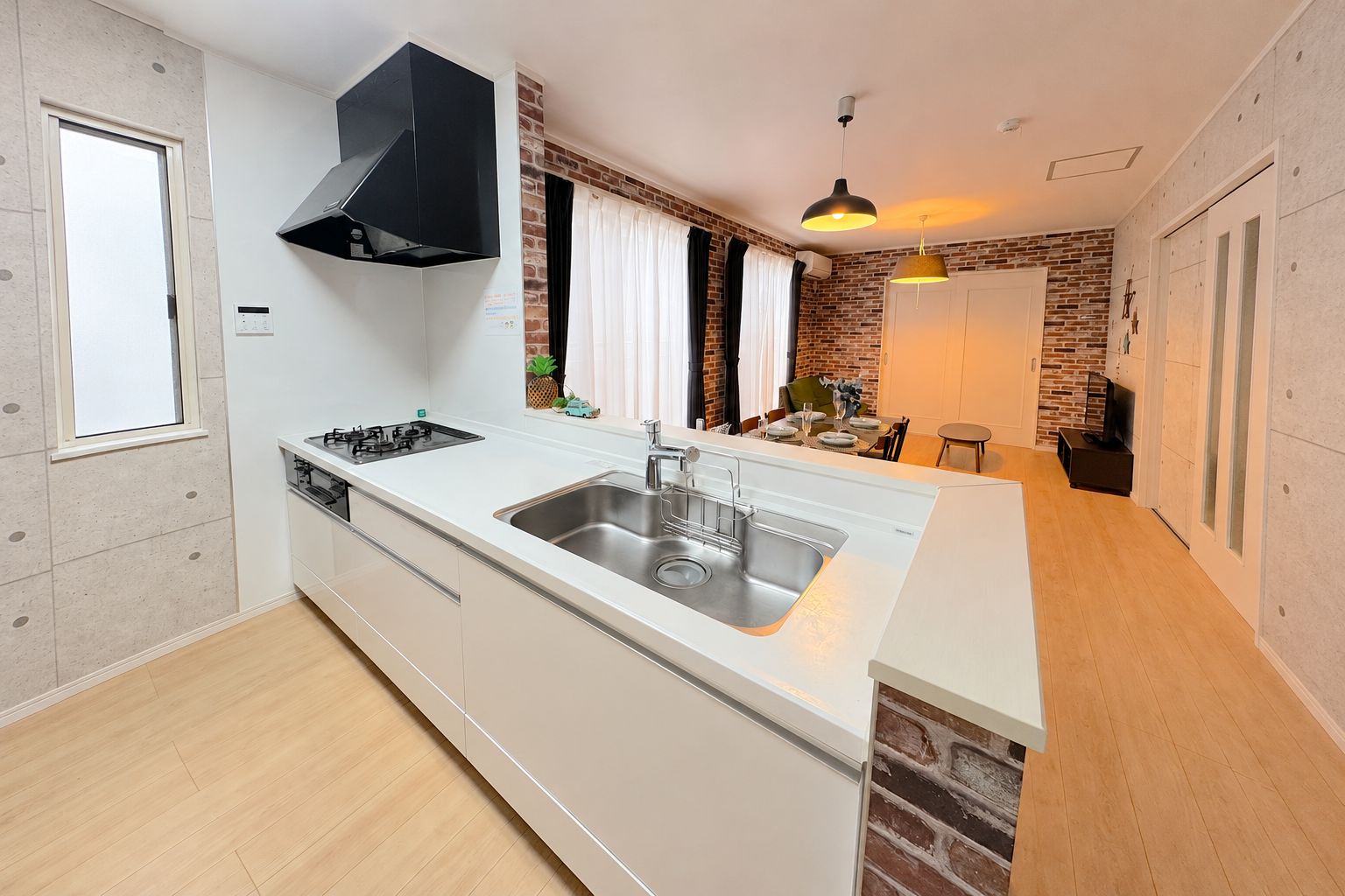 A modern kitchen with a central island, a black range hood, and a brick accent wall.