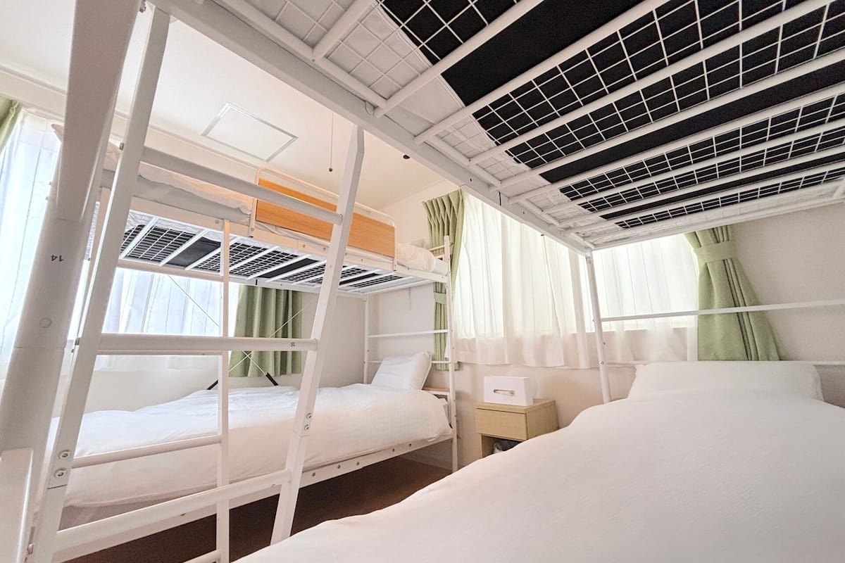 A bunk bed room with a window, a bedside table, and an air conditioning unit.