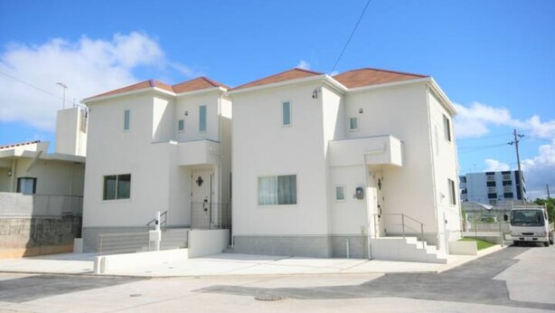 Un edificio moderno de dos pisos con techo plano y un pequeño porche frontal.