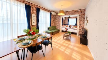 Un salon moderne avec un coin repas, des murs en briques et une grande fenêtre agrémentée de rideaux.