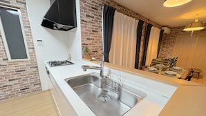 Una cocina moderna con un lavamanos de acero inoxidable, una estufa a gas y una campana extractora negra.