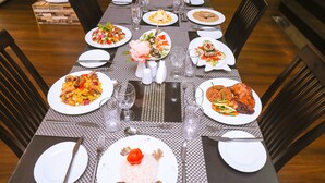 A dining table set with plates of food, cutlery, and glasses. - Mendiata Hotel (Accra)