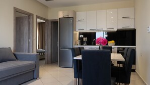 A modern kitchen with white cabinets, a black refrigerator, and a dining area with a table and chairs. - Gramvoussa Bay (Kissamos)