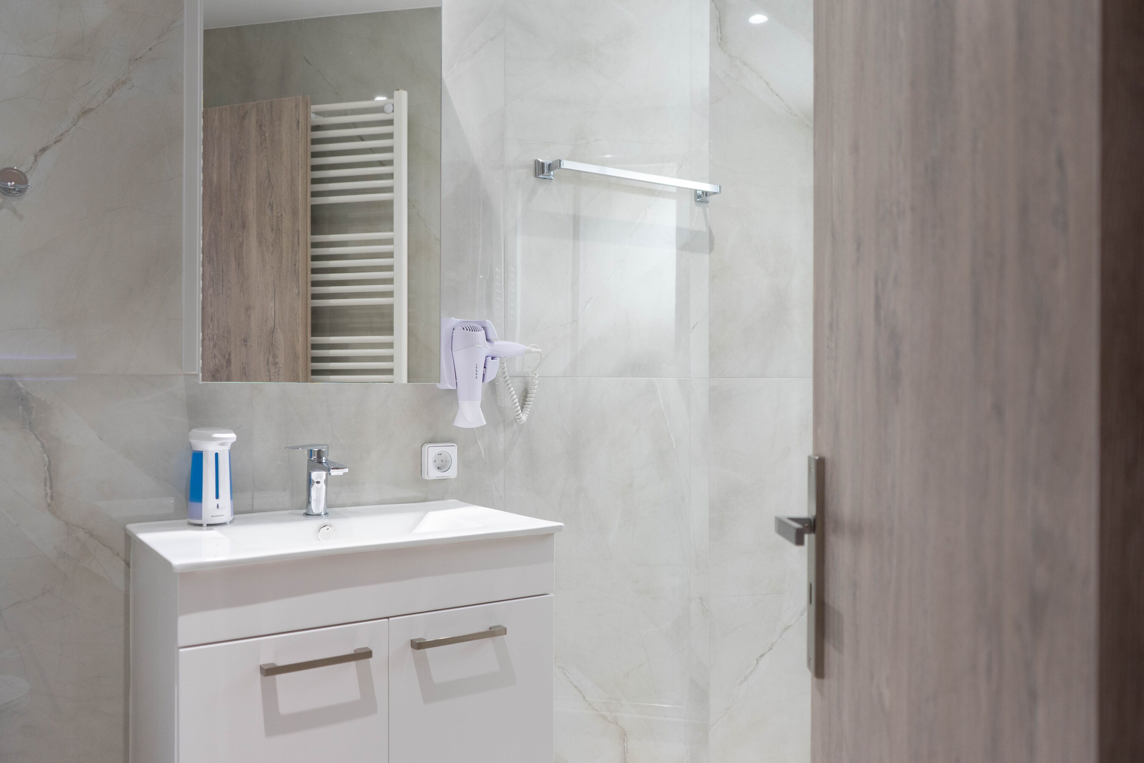 A modern bathroom with a white sink, a mirror, and a towel rack.